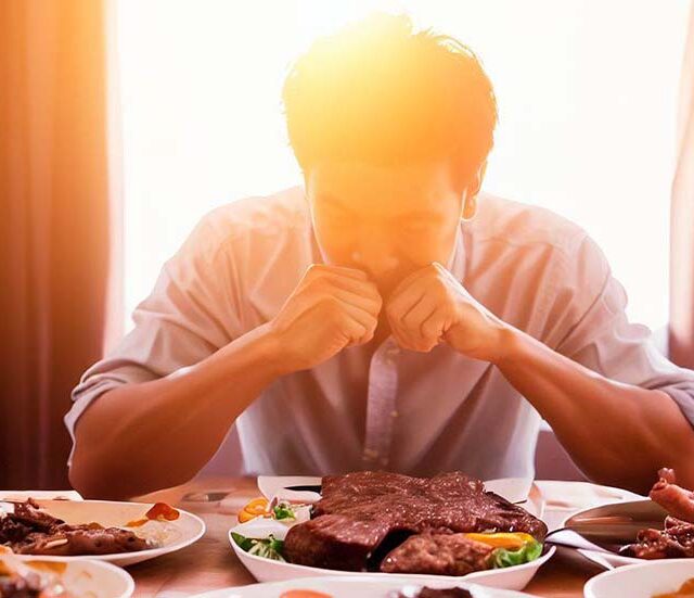 Man eating meat at a table, anxious emotion.